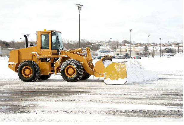 Wheel loader pushing snow in a commercial parking lot